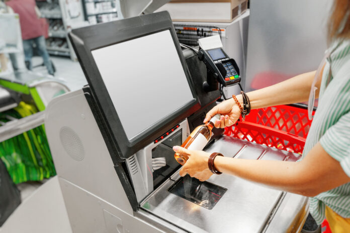 woman using self checkout at supermarket