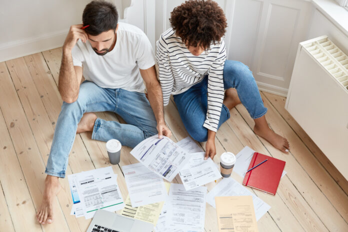 photo-of-couple-trying-to-buy-house-in-netherlands-sitting-on-floor-surrounded-by-bills